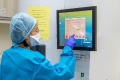 technician in protective gear looking at monitor